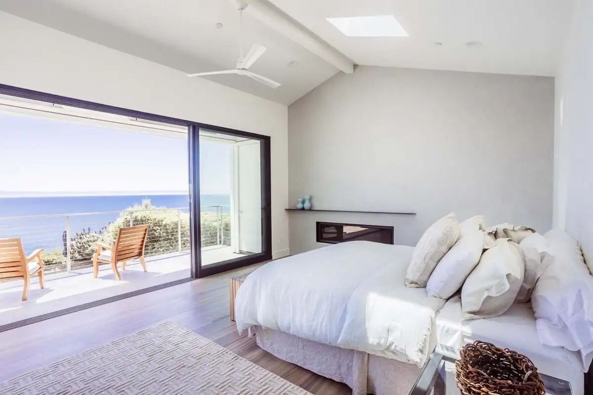 Bedroom with a wall of sliding glass open to a deck above the bay, Sea Cliff project